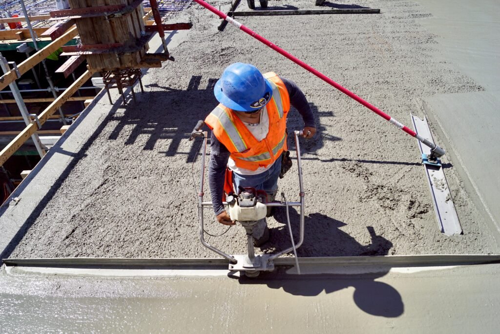 Professional concrete artisan using a vibratory screed for an industrial warehouse floor in Fargo.